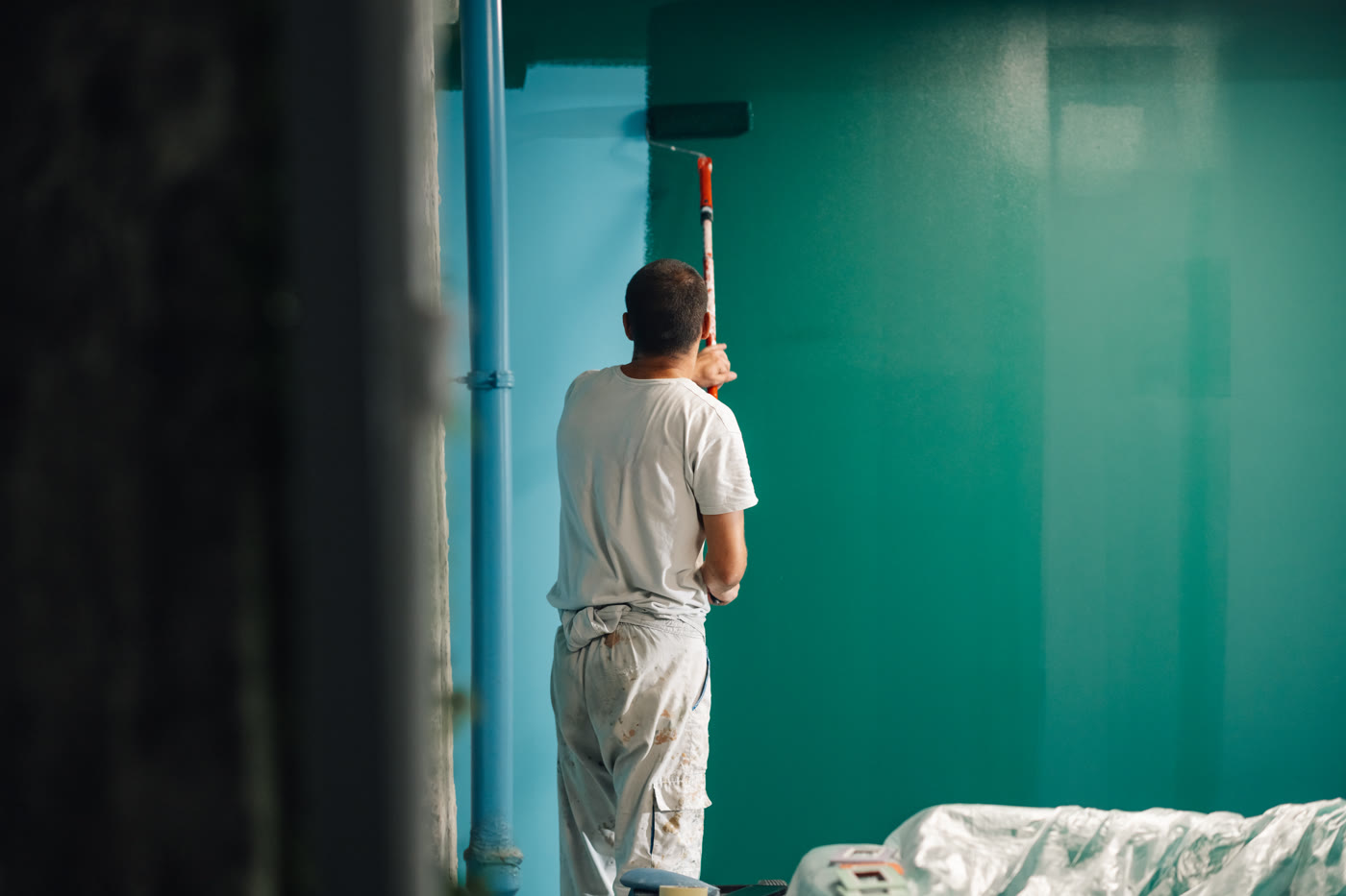 Peintre appliquant une peinture au rouleau sur un mur intérieur
